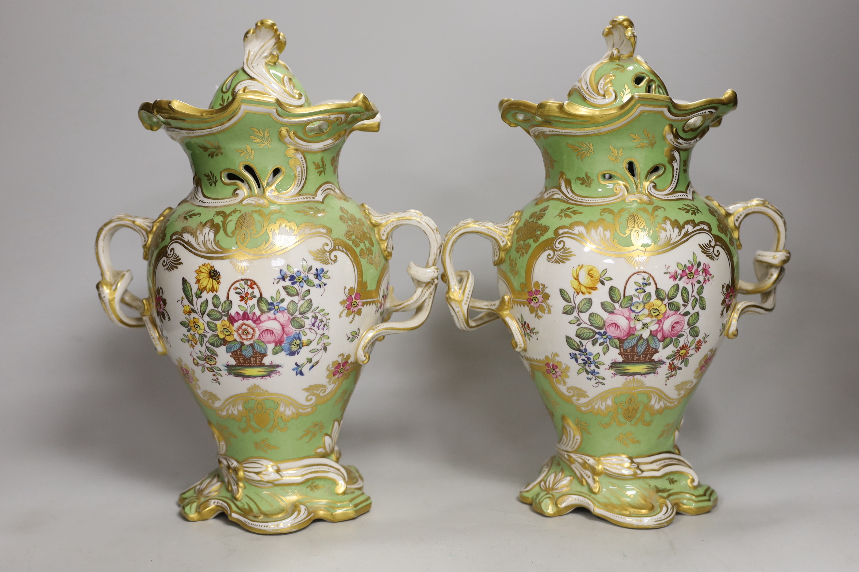 A pair of Rockingham style porcelain pot pourri vases, each of rococo form painted to each side with baskets of flowers, rare brown printed Rockingham griffin mark, 29cm high